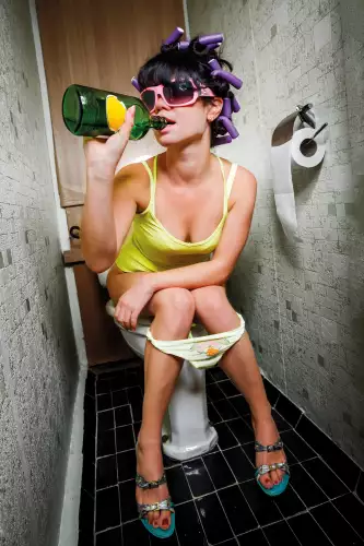 Girl on toilet drinking 